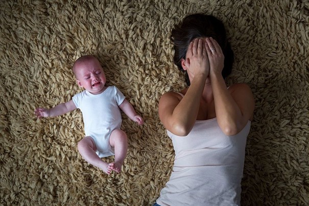 bébé qui pleure près d'un adulte qui se cache les yeux